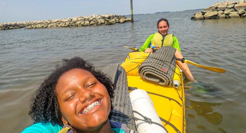 two girls in a kayak smile on an outward bound course